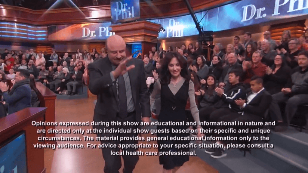 Dr. Phil McGraw and guest interacting on stage during live show with applause from audience.