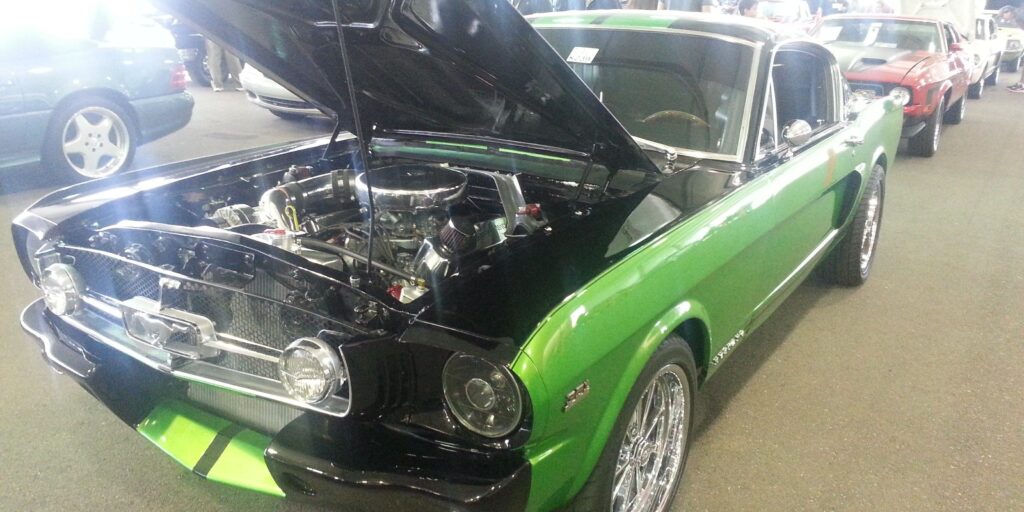Vintage 1960s Ford Mustang GT with open hood at a classic car show.