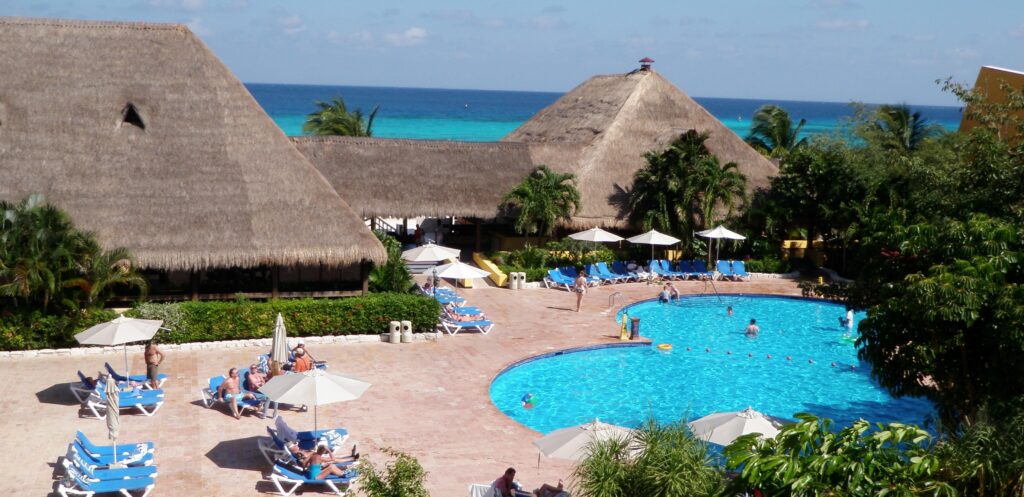 Luxurious Cozumel resort featuring a picturesque free-form pool, ocean views, and tropical thatched-roof accommodations.