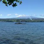 Kayaker enjoying serene Hawaiian lake panorama with lush greenery and distant mountain backdrop.