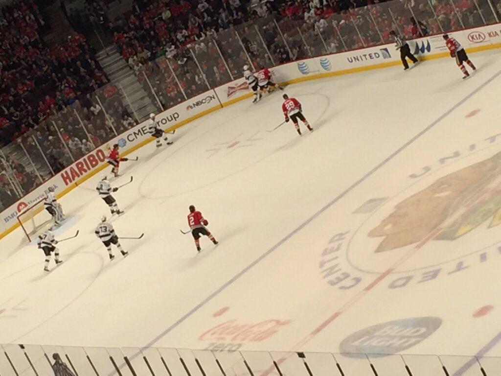Ice hockey match action, Sacramento Kings in red against Chicago Blackhawks in white.