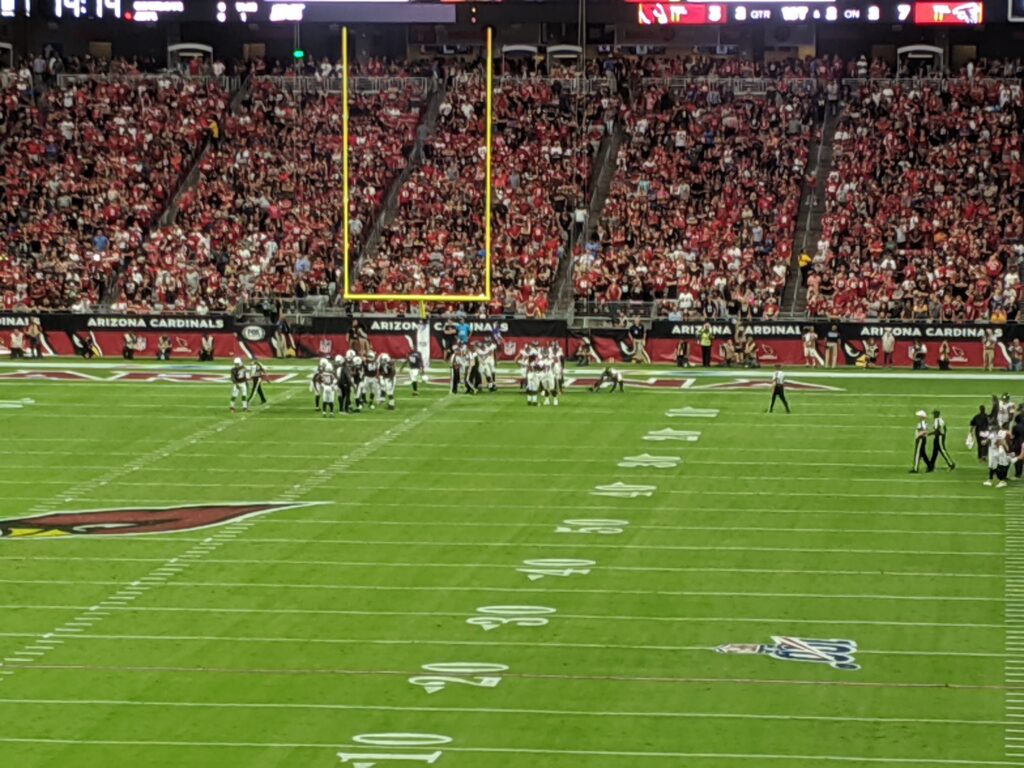 NFL night match - Falcons versus Cardinals in crowded, brightly-lit football stadium.