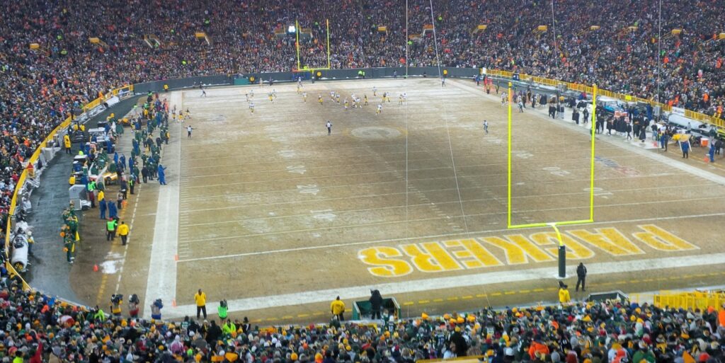 Packers home game at a vibrant, packed American football stadium during a chilly night.
