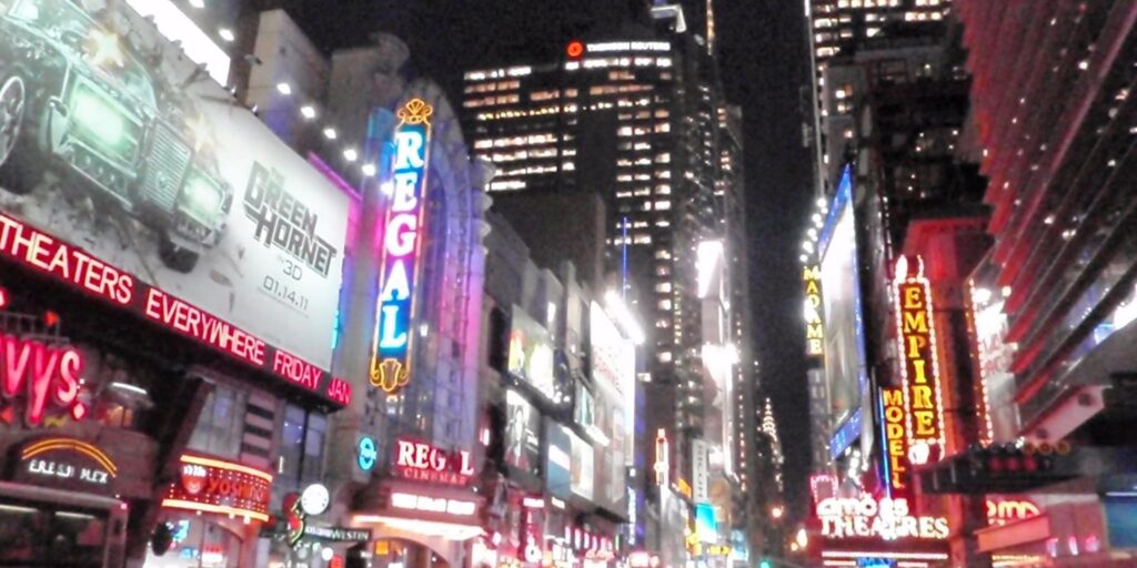 Electric nightlife scene in Times Square, NYC with neon billboards and theater signs.