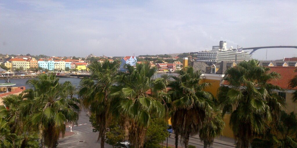 Palm-lined promenade and cruise ship in Willemstad, Curacaos vibrant tropical harbor.