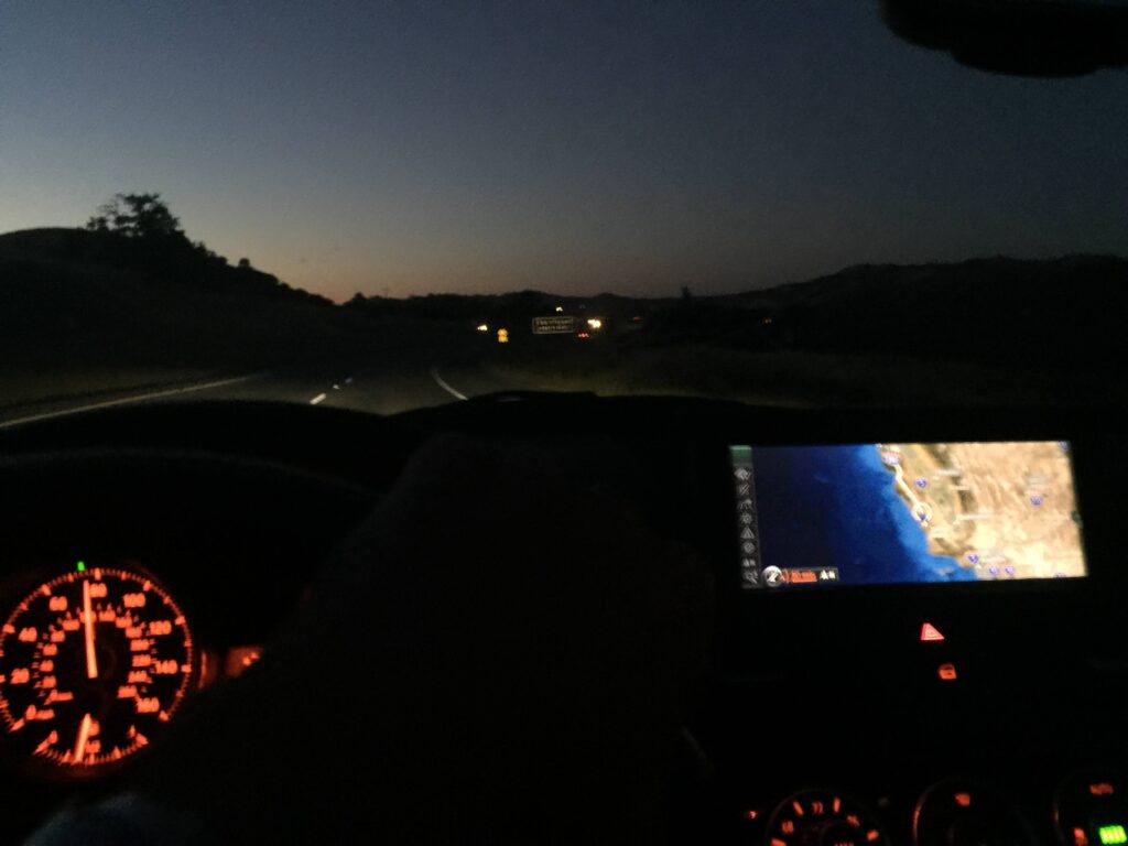 Twilight highway drive, view from car with illuminated dashboard and active GPS system.